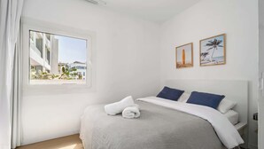 Une chambre à coucher avec un lit, une fenêtre et deux tableaux encadrés accrochés au mur.