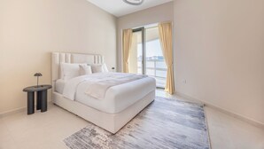 Une chambre moderne avec un grand lit, une table de chevet et une vue sur l’extérieur grâce à une porte coulissante.