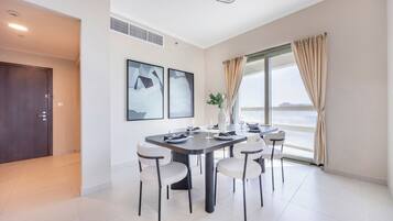 Ein modernes Esszimmer mit einem großen Tisch, sechs Stühlen und Meerblick durch ein großes Fenster.