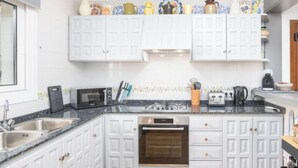 A kitchen with white cabinetry, a microwave, a toaster, and a stove. - Villa Kernow by Interhome (Moraira)