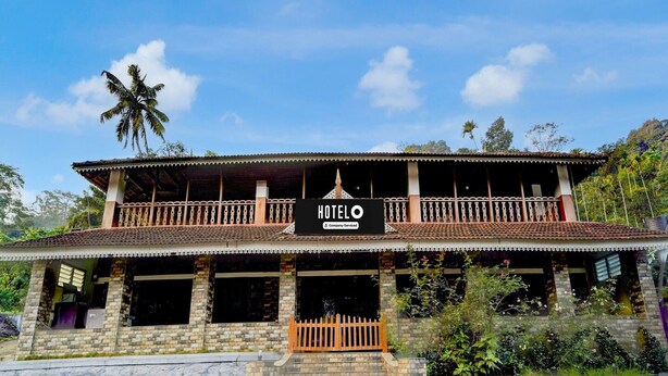A two-story hotel with a balcony, a signboard, and a tiled roof. - Deluxe Kallar Vattiyar Waterfalls Munnar (Devikolam)