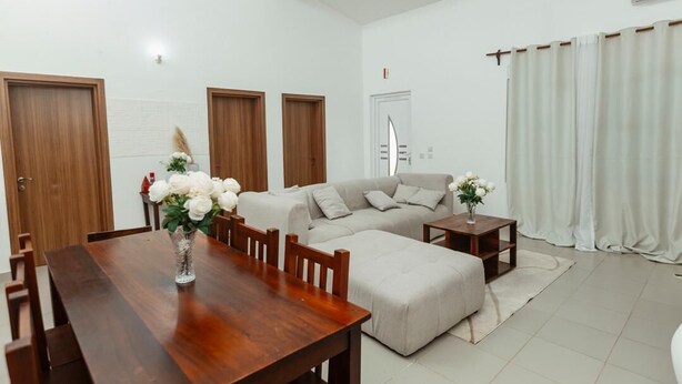 A modern living room with a wooden dining table, a sofa, and a small side table. - Perfect 3-bedroom apartment with AC in welcoming West B Zanzibar (West B, Zanzibar)