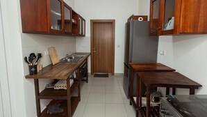 A compact kitchen with wooden cabinets, a stainless steel sink, and a refrigerator. - Perfect 3-bedroom apartment with AC in welcoming West B Zanzibar (West B, Zanzibar)