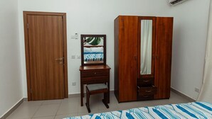 A bedroom with a wooden wardrobe, a desk with a chair, and a bed. - Perfect 3-bedroom apartment with AC in welcoming West B Zanzibar (West B, Zanzibar)