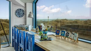 A room with a large window, a desk with art supplies, and a view of the beach. - "Ajvi" - 250m from the sea by Interhome (Løkken)