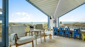 A covered outdoor seating area with chairs and tables, overlooking a beach. - "Ajvi" - 250m from the sea by Interhome (Løkken)