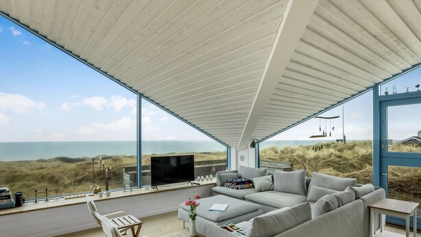 A modern living room with a large sofa, a TV, and a dining area with chairs and a table. - "Ajvi" - 250m from the sea by Interhome (Løkken)