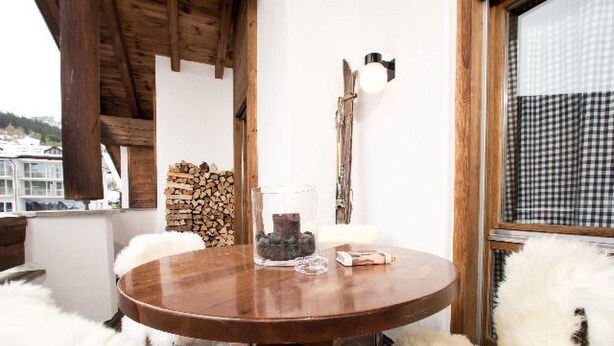 Een ronde houten tafel met een glazen vaas, een kaars en een boek.