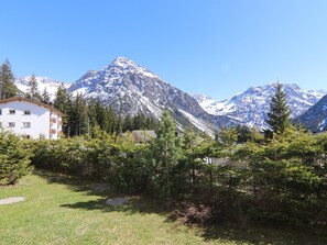 A mountain landscape with snow-capped peaks, a building with balconies, and a grassy foreground with trees. - Chesa Forma 2 by Arosa Holiday Appartement/Fewo, Dusche oder Bad, WC, 6-Bettwohn by Interhome (Arosa)