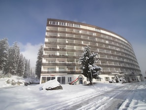 A multi-story hotel with balconies, a snow-covered ground, and a building with a sign for a pizzeria. - Alexandra 611 by Arosa Holiday Appartement/Fewo, Bad, WC, 4-Bettwohnung by Interhome (Arosa)