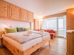 Een hotelkamer met een houten bed, een bank en een groot raam.