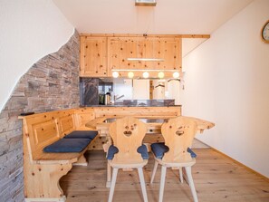 Een keuken met houten kasten, een inbouwbank en een eethoek met stoelen.