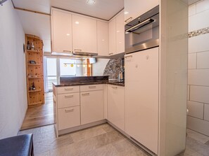A modern kitchen with white cabinetry, a stainless steel oven, and a stone backsplash. - Alexandra 611 by Arosa Holiday Appartement/Fewo, Bad, WC, 4-Bettwohnung by Interhome (Arosa)