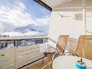 A balcony with a view of a snowy mountain and a town below. There are two chairs and a table on the balcony. - Alexandra 611 by Arosa Holiday Appartement/Fewo, Bad, WC, 4-Bettwohnung by Interhome (Arosa)