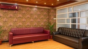 Een hotellobby met twee leren banken, een houten plafond en behang met een patroon.