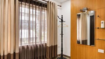 A room with a coat rack, a mirror, and curtains.