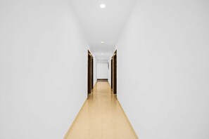 A long, narrow hallway with white walls and a wooden floor.