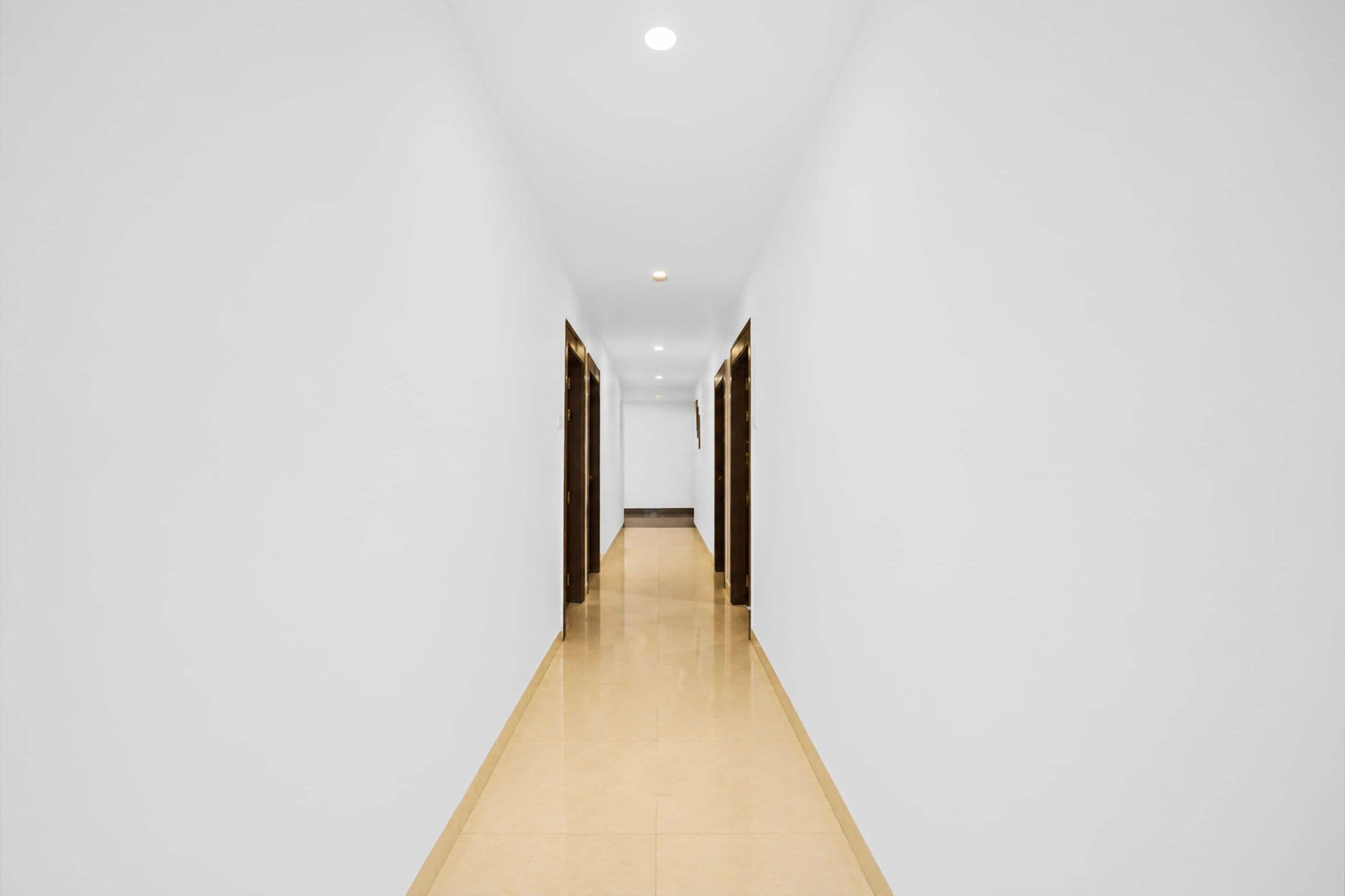 A long, narrow hallway with white walls and a wooden floor.