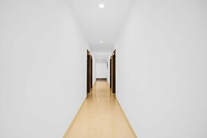 A long, narrow hallway with white walls and a wooden floor. - Hotel O Bhangagarh (Guwahati)