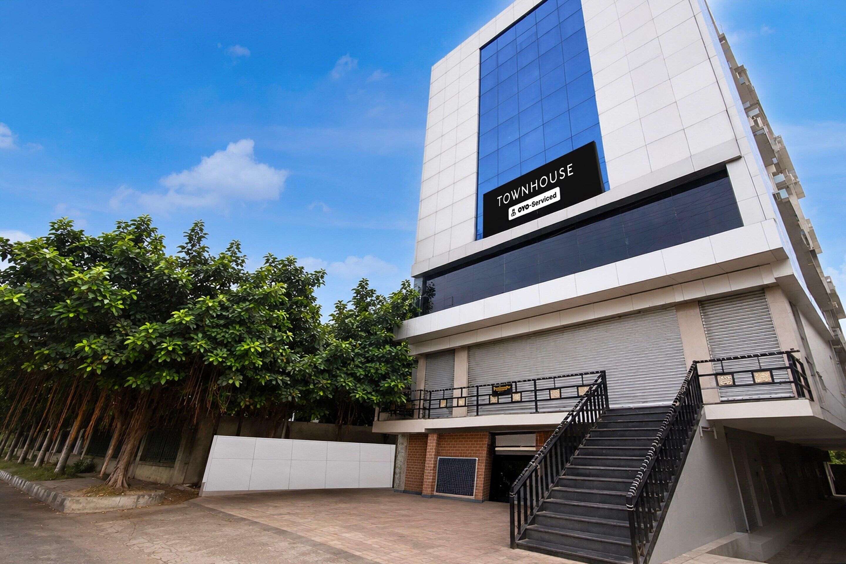 A modern building with a sign reading 'TOWNHOUSE' and 'OYO-Serviced'.