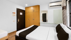 Een hotelkamer met een bed, kast, nachtkastje en spiegel.