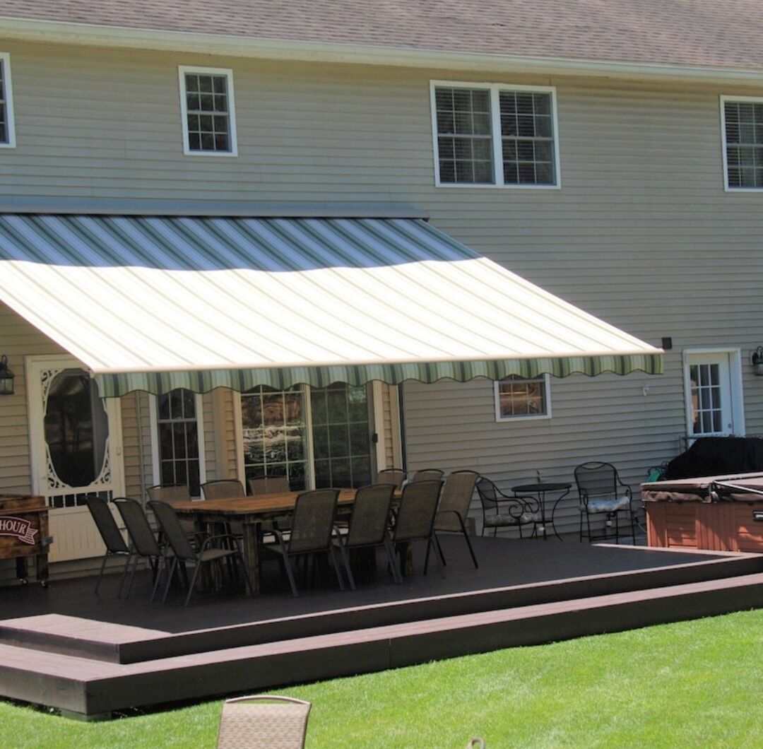 A covered patio with a dining table and chairs, a grill, and a small stage area.