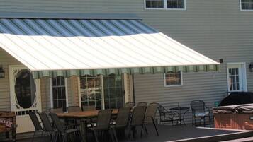 A covered patio with a dining table and chairs, a grill, and a small stage area.