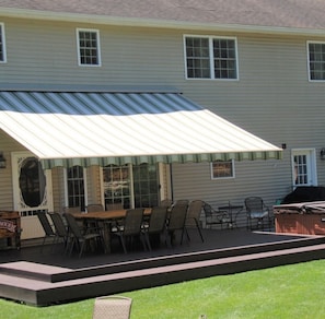 A covered patio with a dining table and chairs, a grill, and a small stage area.
