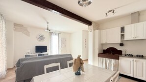 Ein modernes Zimmer mit einem Bett, einem Esstisch, einem Fernseher und einer Küchenzeile.