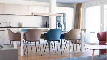 Una cocina moderna con armarios blancos, un comedor con cuatro sillas y un amplio ventanal con cortinas.