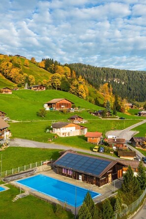 Ländliche Umgebung mit Schwimmbad, Holzhäusern und hügeliger Landschaft.