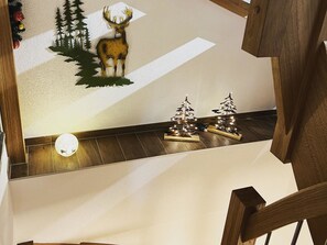 Eine Holztreppe mit einer Wandverkleidung, die einen Hirsch und Weihnachtsbäume zeigt.