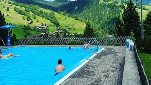 Una piscina con vista a colinas verdes y una bandera.