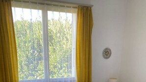Een kamer met twee bedden, een raam met gordijnen, een wandklok en een bedlampje.