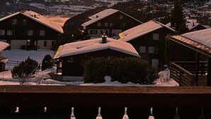Een bergdorp met met sneeuw bedekte daken en gebouwen, gelegen voor een zonsondergang.