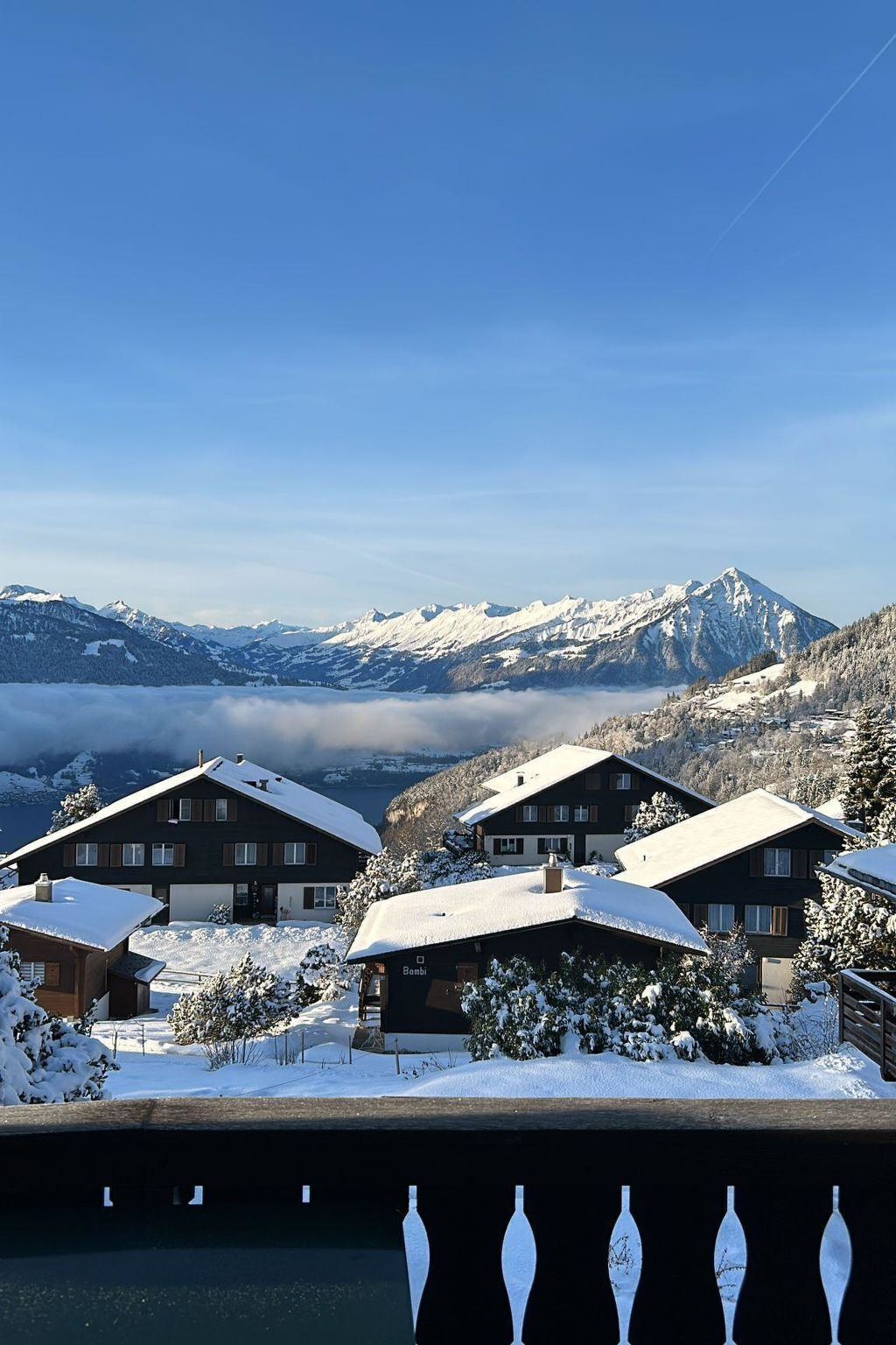 Un village de montagne enneigé, avec des bâtiments de style chalet, un ciel dégagé et une vue sur les montagnes lointaines.