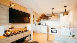 A modern kitchen with a flat-screen TV, wooden cabinets, and a dining area with a table and chairs. - Relax Suite With Jacuzzi (Burg-Reuland)
