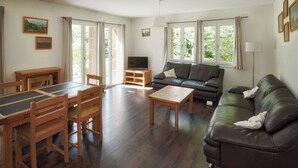 Et møbleret opholdsstue med sofa, sofabord, spisebord, stole og et fjernsyn.