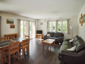 A furnished living room with a sofa, coffee table, dining table, chairs, and a TV. - CityChalet Appartement/Fewo Silberdistel**** by Interhome (Interlaken)