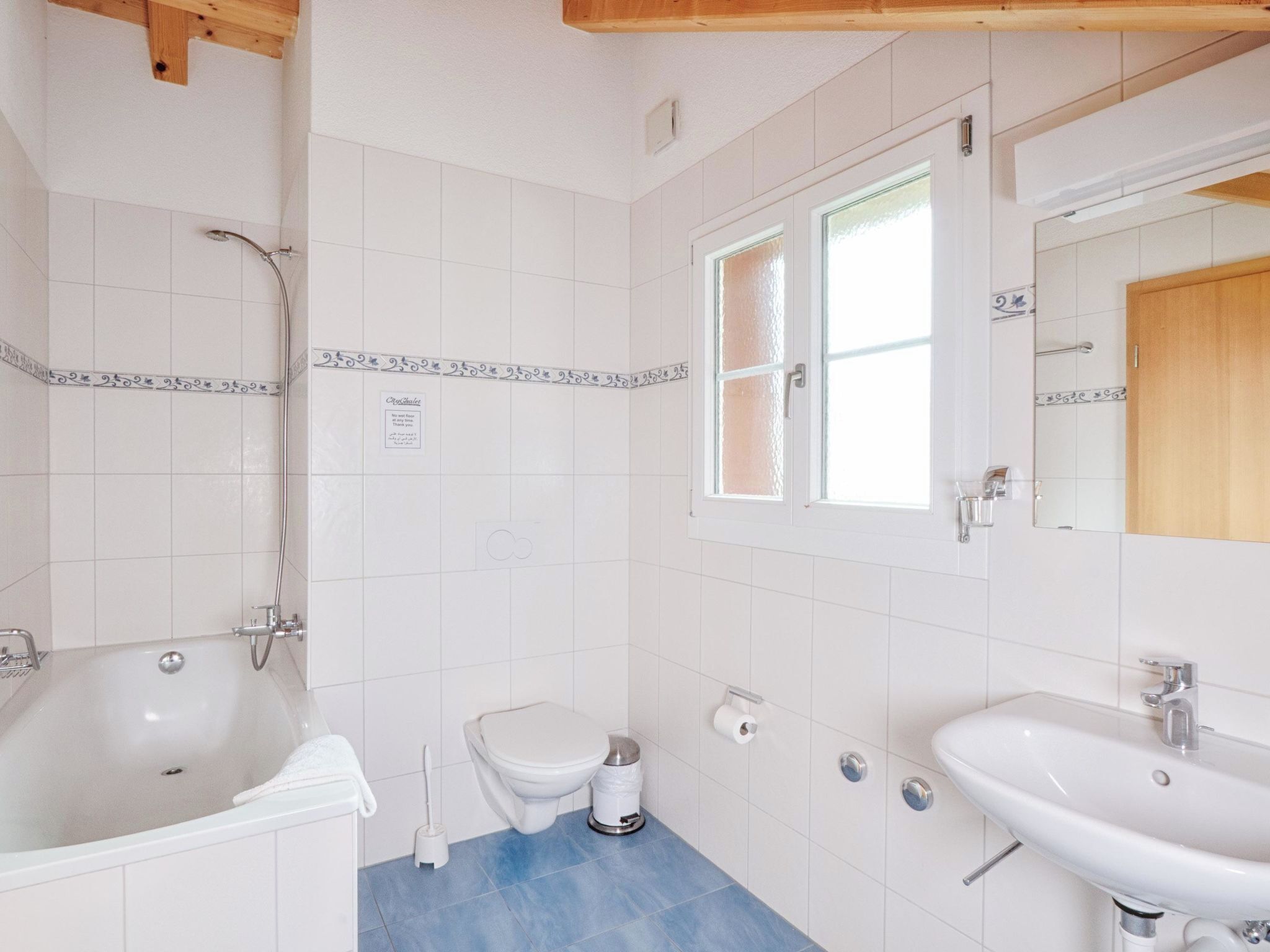 A bathroom with a bathtub, toilet, sink, and a window.