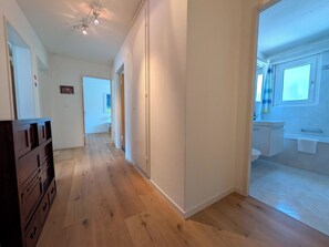A hallway with wooden flooring leading to a bathroom with a toilet and sink. - Sunnaboda 1 by Arosa Holiday Appartement/Fewo, Dusche oder Bad, WC, 4-Bettwohnun by Interhome (Arosa)