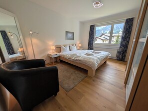 Une chambre d’hôtel comprenant un lit, des tables de chevet, un bureau, une chaise, une grande fenêtre avec vue et une lampe de sol.