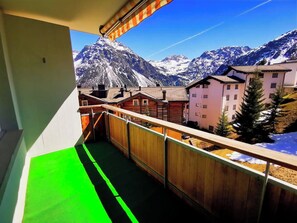 Un balcon offrant une vue sur des montagnes enneigées et sur une ville située en contrebas.