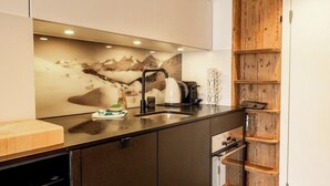 A modern kitchen with a black countertop, a built-in oven, and a wooden cabinet. - Utoring Hohe Promenade 404 Appartement/Fewo, Dusche und Badewanne, 1 Schlafraum by Interhome (Arosa)
