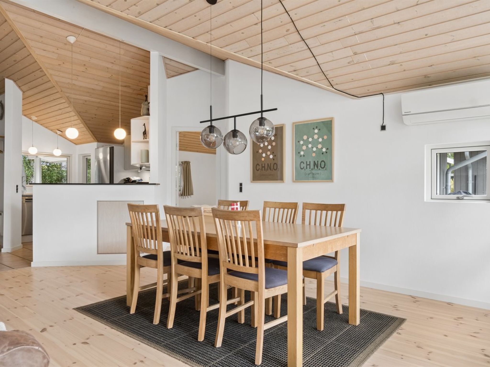 A modern kitchen with a dining area, wooden ceiling, pendant lights, and a kitchen island.