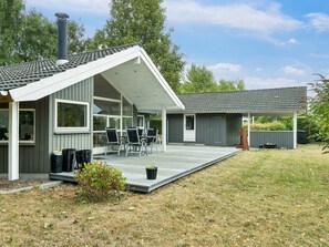 Une maison moderne dotée d’un patio couvert, d’une cheminée et d’une terrasse.