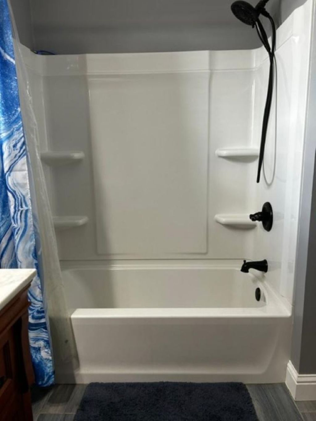 Eine weiße Badewanne mit Duschbrause, Ablagefläche und Wasserhahn.