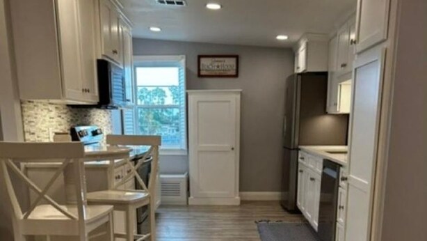 A kitchen with white cabinets, a dining area with white chairs, and a window with a view. - Coastal Retreat Charming and Salty in St. Andrews/Panama City Florida (Panama City)