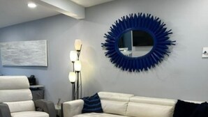 A modern living room with a sectional sofa, a wooden coffee table, and a decorative mirror on the wall. - Coastal Retreat Charming and Salty in St. Andrews/Panama City Florida (Panama City)