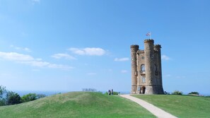 A stone tower with a flag, surrounded by a grassy hill and a clear sky. - Lemon Tree Cottage - sleeps 4 guests, countryside, Broadway (Broadway)